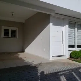 Fachada externa de uma residência branca com porta branca em Lajeado, Brasil.