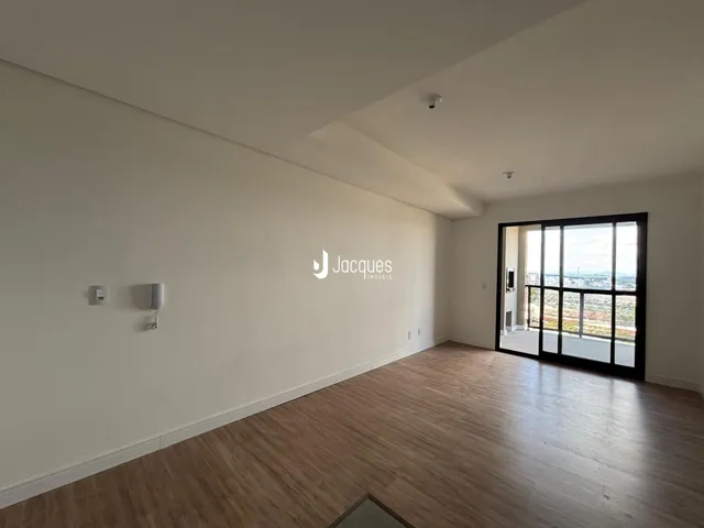 Sala de estar com piso de madeira e grande janela de vidro.