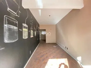 Corredor interno com piso de madeira e parede escura decorada com desenhos a giz.