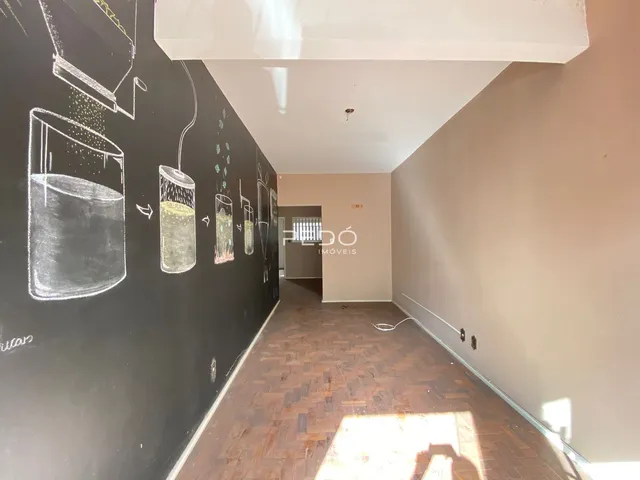 Corredor interno com piso de madeira e parede escura decorada com desenhos a giz.