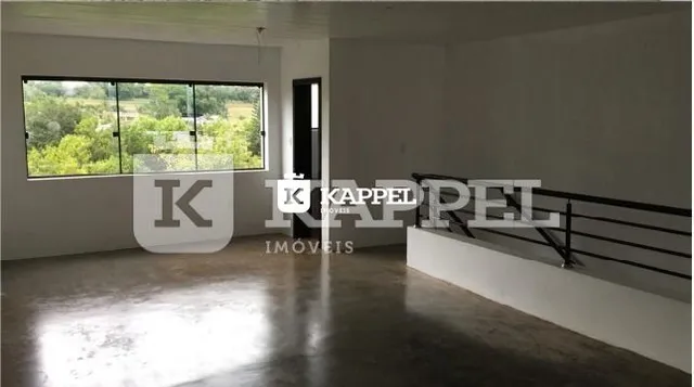 Uma sala ampla com grandes janelas que oferecem vista para a vegetação externa.