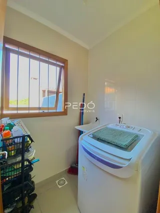 Vista interna de um cômodo com janela e máquina de lavar roupa.