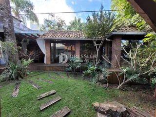 Vista da fachada de uma residência com jardim e vegetação.