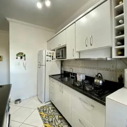 Foto de uma cozinha com armários brancos e bancadas escuras.