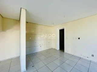 Um corredor interno com piso de cerâmica e paredes brancas.