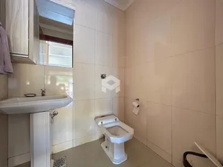 Banheiro com piso e paredes de cerâmica brancas.