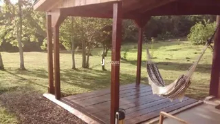 Vista externa de uma estrutura de madeira em Lajeado, Brasil, cercada por gramado e árvores.