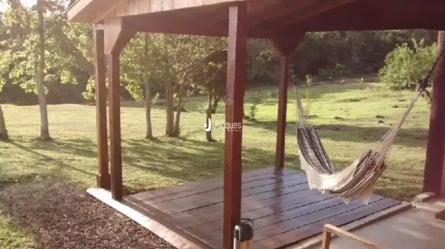 Vista externa de uma estrutura de madeira em Lajeado, Brasil, cercada por gramado e árvores.