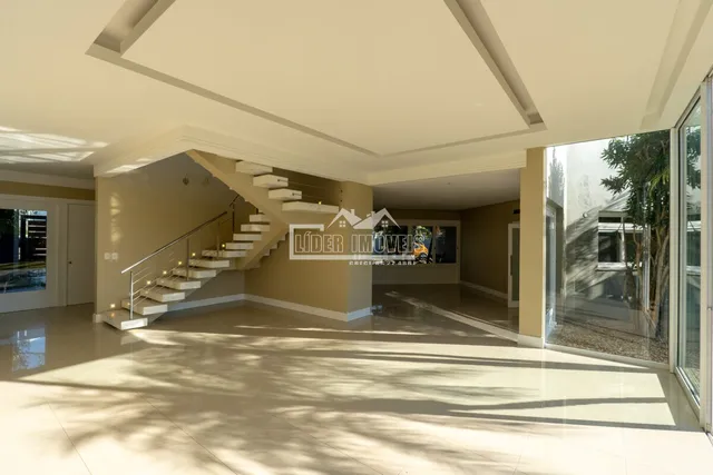 Sala de estar com escadaria e portas de vidro.