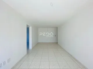 Interior de um ambiente longo com paredes brancas e piso de cerâmica claro.