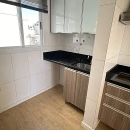 Foto de uma cozinha com armários brancos e piso de madeira clara.