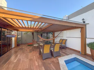 Área externa com deck de madeira, mobiliário e piscina.