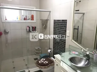 Banheiro com box de vidro e piso cerâmico.