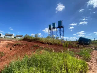 Vista externa de uma área com estruturas metálicas e vegetação em um dia ensolarado.