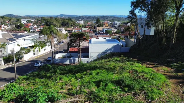 Vista panorâmica da propriedade com vegetação no primeiro plano e paisagem urbana ao fundo.
