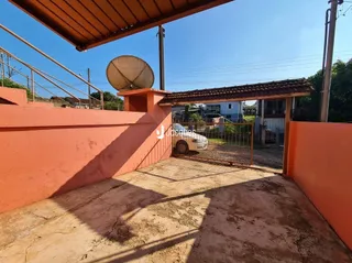Vista externa de um pátio com parede laranja e piso de concreto.