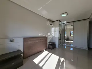 Quarto com cabeceira estofada e piso de porcelanato claro.
