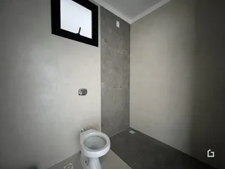 Foto de um banheiro interno com piso de concreto e azulejos brancos.