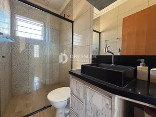 Foto de um banheiro com box de vidro e bancada escura.