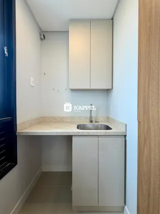 Uma cozinha moderna com armários brancos e bancada clara.