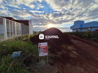 Foto externa de uma propriedade com terreno aberto e edifícios ao fundo.