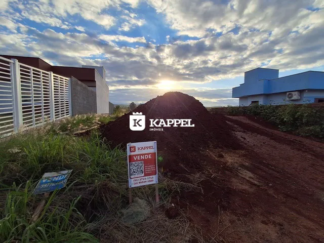 Foto externa de uma propriedade com terreno aberto e edifícios ao fundo.