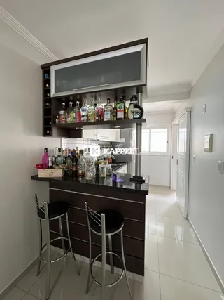 Bancada de cozinha escura com prateleiras de bebidas e banquetas.