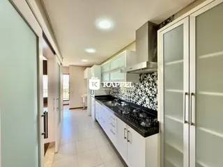 Esta é uma cozinha com armários brancos e bancadas escuras.