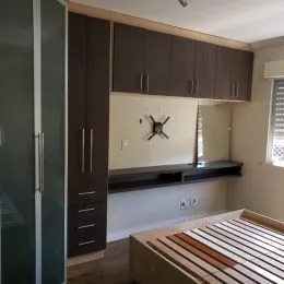 Quarto com armários escuros e cama visível.