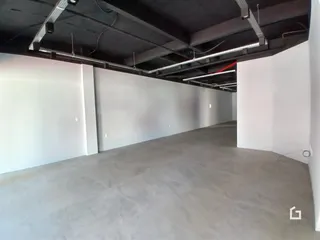 Interior de um espaço com teto de concreto aparente e paredes brancas.