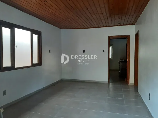 Ambiente interno de uma sala com piso de cerâmica e teto de madeira.