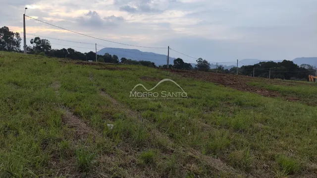 Paisagem de campo gramado com colinas ao fundo.