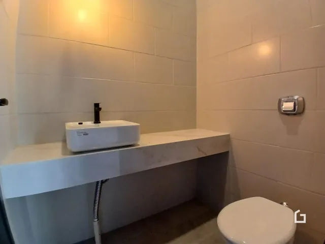 Foto de um banheiro moderno com bancada e vaso sanitário.