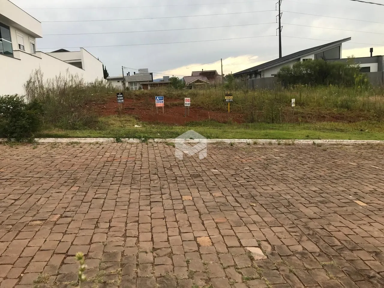Vista externa de um terreno pavimentado com vegetação ao fundo.