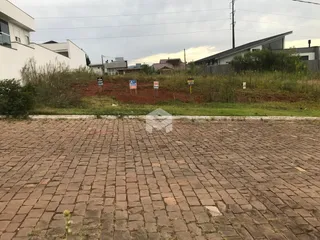Vista externa de um terreno pavimentado com vegetação ao fundo.