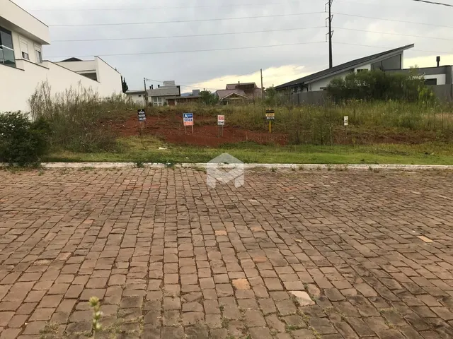 Vista externa de um terreno pavimentado com vegetação ao fundo.