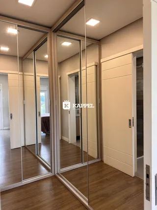 Hall de entrada com piso de madeira e espelhos grandes em um imóvel.
