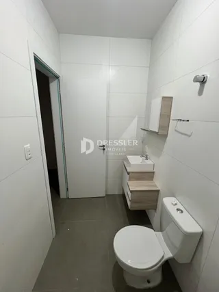 Foto de um banheiro com revestimento branco e bancada de madeira.
