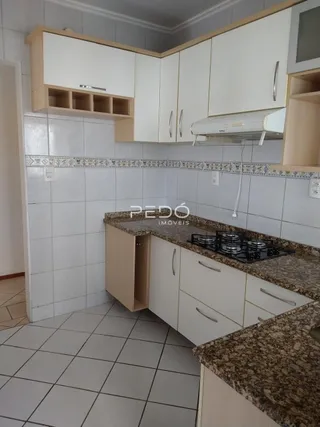 Foto de uma cozinha com armários brancos e bancadas de granito.
