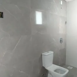 Foto de um banheiro com azulejos brancos e vaso sanitário.