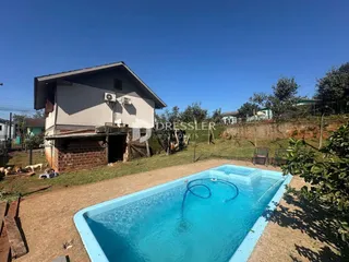 Foto da fachada de uma casa com piscina no quintal.