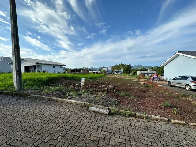 Vista externa da propriedade mostrando um pavimento de tijolos e área gramada.