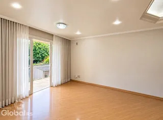 Sala de estar com piso de madeira e cortinas brancas.