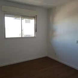 Vista interna de um cômodo com piso de madeira e janela.
