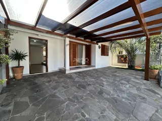 Área externa pavimentada com piso de pedra e estrutura de madeira.