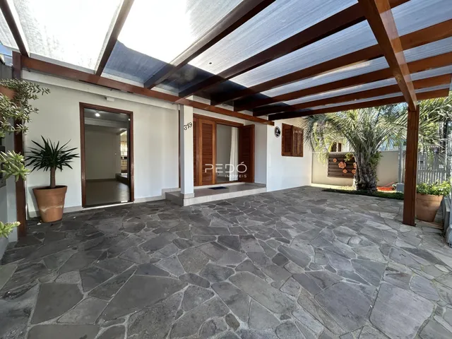 Área externa pavimentada com piso de pedra e estrutura de madeira.