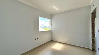 A sala apresenta paredes brancas e uma grande janela com vista.