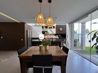 Foto de uma sala de jantar com mesa de madeira e cozinha moderna em um imóvel.