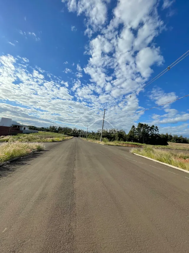 Foto de uma estrada asfaltada sob um céu azul com nuvens.