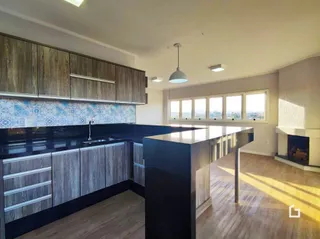 Vista da cozinha moderna com armários escuros e bancada escura.